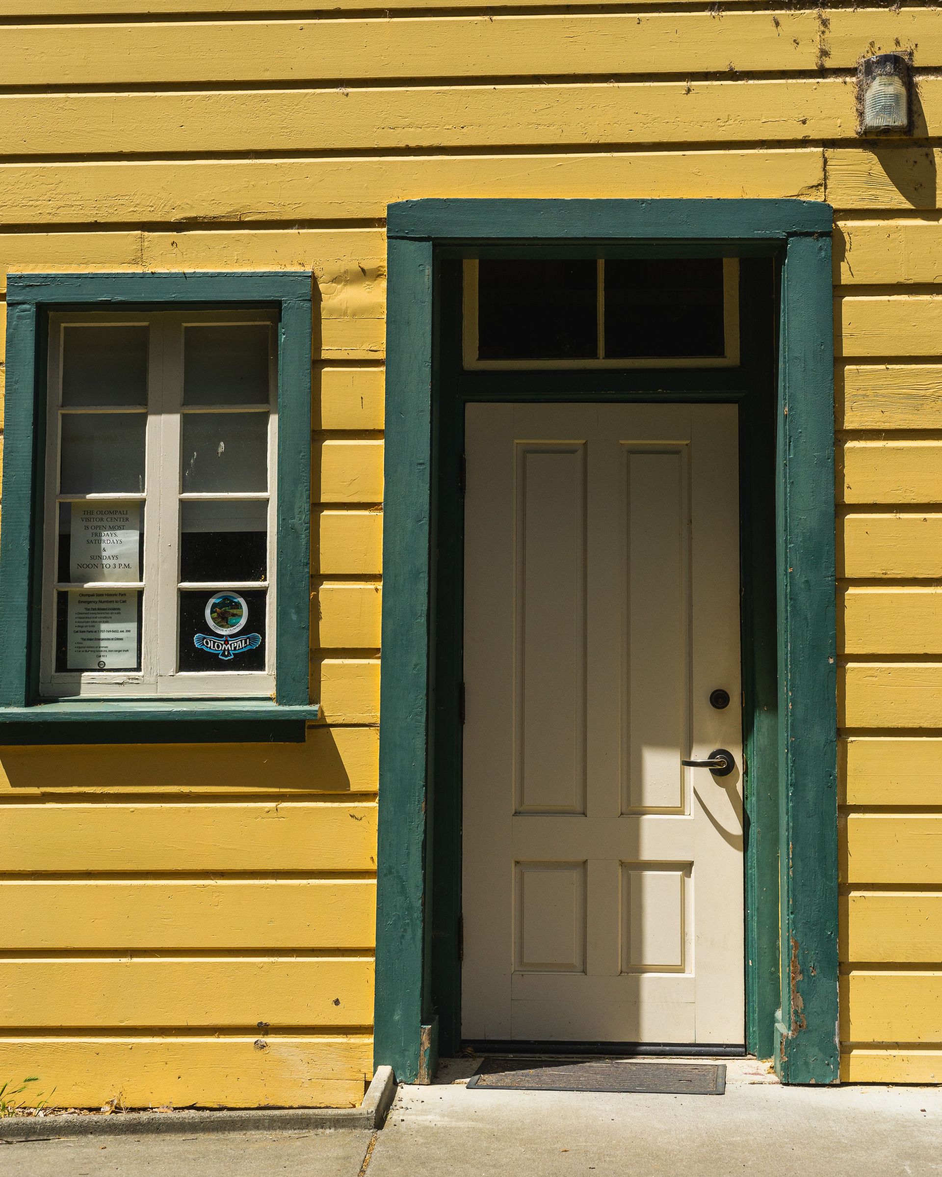 Charming yellow house with a wooden facade, green trim, and an inviting entrance.