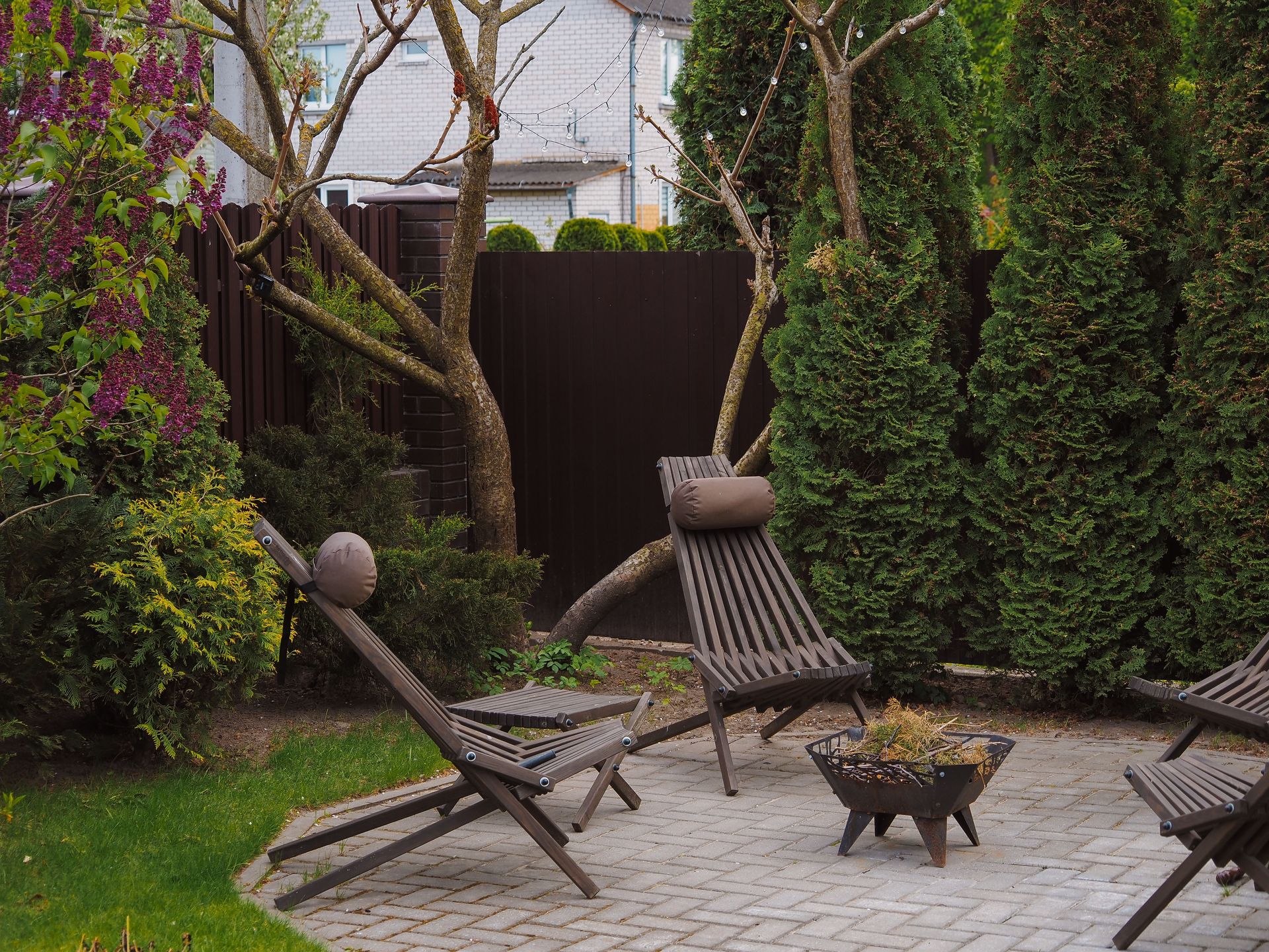 Cozy backyard featuring wooden lounge chairs and lush greenery, perfect for relaxation.